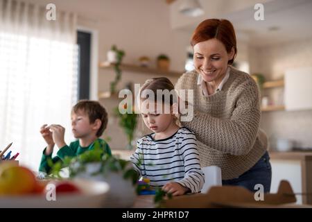 Mutter von kleinen Kindern, die sie beim Spielen mit Baukasten zu Hause überstehen. Stockfoto