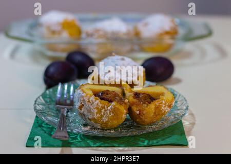 Süße Pflaumenknödel auf einem Teller auf dem Tisch. Hausgemachtes Dessert mit Kartoffeln und Pflaumen. Stockfoto