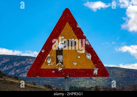 Biegen Sie in Straßenschild mit Einschusslöchern, das kleine Bergdorf Kefalari, Peleponesse, Griechenland Stockfoto