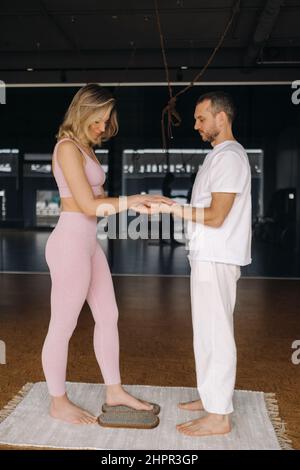 Ein Mann und eine Frau machen Yoga auf Brettern mit Nägeln im Fitnessstudio. Stockfoto