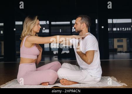 Eine Frau und ein Mann üben im Fitnessstudio Yoga-Paarturnen aus. Stockfoto