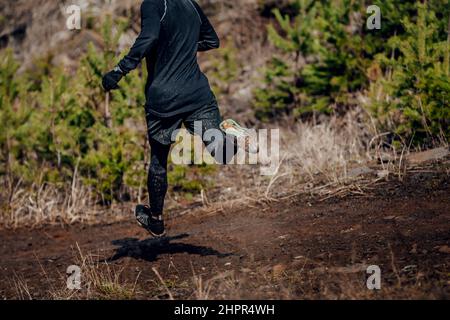 Männlicher Läufer läuft auf schlammigem Trail den Berg hinunter Stockfoto