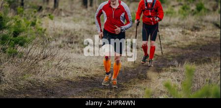 Zwei männliche Läufer führen ein Schlammtrail-Rennen im Wald durch Stockfoto