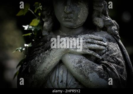 Gebetsengel faltete die Arme über die Brust Fragment einer sehr alten Steinstatue. Stockfoto