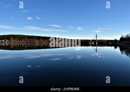 Jätkänkynttilä, Holzfällerkerzenbrücke in Rovaniemi. Wasserspiegelung auf einem See. Ruhiges Wasser. Spiegeleffekt. Blauer Himmel. Lappland. Finnland. Stockfoto