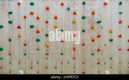 Farbenfrohe Klettergriffe an einer Kletterwand aus Holz Stockfoto