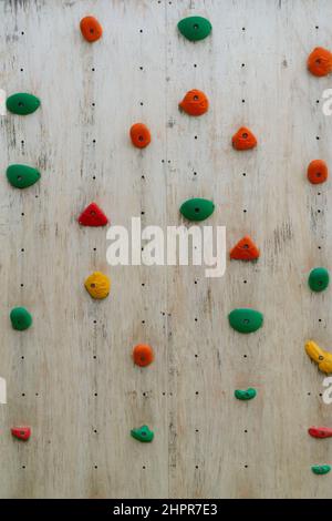 Farbenfrohe Klettergriffe an einer Kletterwand aus Holz Stockfoto