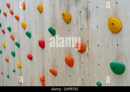 Farbenfrohe Klettergriffe an einer Kletterwand aus Holz Stockfoto