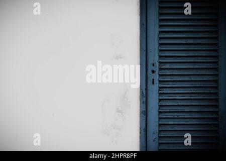 Weiße Grunge Zementwand und alte blaue Tür Hintergrund. Stockfoto