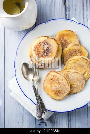 Ein Teller voller Apfelpfannkuchen, überzogen mit Zucker, serviert mit Vanillepudding