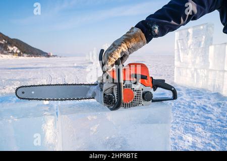 Eisskulpturen machen. Ein Mann hält eine Benzinsäge am Baikalsee. Stockfoto
