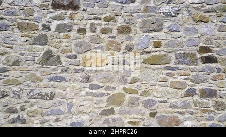 Die Steinmauer. Vorderansicht und Nahaufnahme. Wand aus verschiedenfarbigen Steinen. Stockfoto