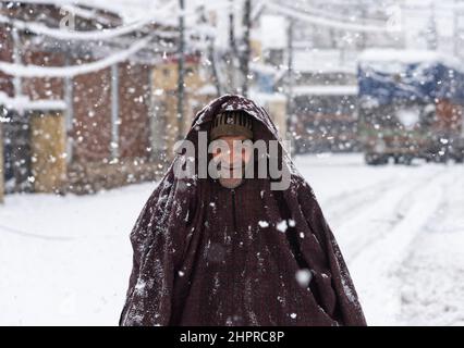 Kaschmir, Indien , 23/02/2022, Srinagar, Indien. 23rd. Februar 2022. Ein Mann zieht seine Jacke während des starken Schneefalls in Srinagar über seinen Kopf.das Kaschmir-Tal erwachte am Mittwochmorgen zu einer schweren Schneedecke, die das normale Leben der Menschen gestört hat. Der Flugbetrieb, der Oberflächentransport und die Routineaktivitäten des Lebens kamen zum Stillstand. Kredit: SOPA Images Limited/Alamy Live Nachrichten Stockfoto