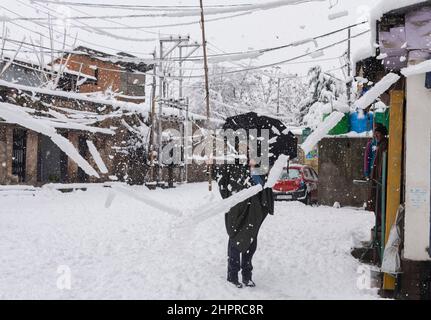 Kaschmir, Indien , 23/02/2022, Srinagar, Indien. 23rd. Februar 2022. Ein Mann räumt bei starkem Schneefall in Srinagar Schnee von den Drähten.das Kaschmir-Tal erwachte am Mittwochmorgen zu einer schweren Schneedecke, die das normale Leben der Menschen gestört hat. Der Flugbetrieb, der Oberflächentransport und die Routineaktivitäten des Lebens kamen zum Stillstand. Kredit: SOPA Images Limited/Alamy Live Nachrichten Stockfoto