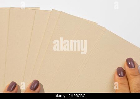 Frau Hände legen Stapel von grau-braunen Karton rechteckige leere Etiketten für Kleidung auf weißem Hintergrund, so dass sie Fan ähneln. Anhänger im Modell. Kopieren Stockfoto