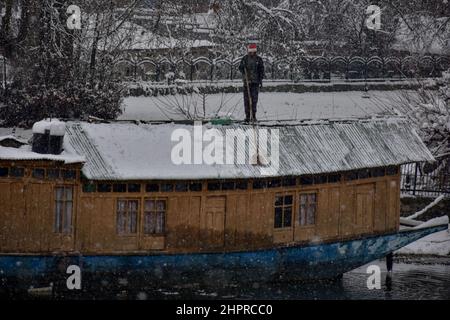 Kaschmir, Indien , 23/02/2022, Srinagar, Indien. 23rd. Februar 2022. Ein Mann räumt Schnee von seinem Hausboot während des starken Schneefalls in Srinagar.die meisten Gebiete des Kaschmir-Tals am Mittwoch erhielten Schneefall - der erste schwere Fall der Saison in den Ebenen - was den Flug- und Eisenbahnbetrieb störte und zur Schließung der lebenswichtigen Srinagar-Jammu-Nationalstraße führte, sagten Beamte hier. Kredit: SOPA Images Limited/Alamy Live Nachrichten Stockfoto