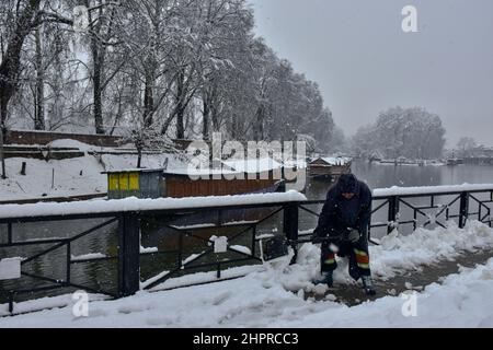 Kaschmir, Indien , 23/02/2022, Srinagar, Indien. 23rd. Februar 2022. Ein Regierungsangestellter räumt während des starken Schneefalls in Srinagar Schnee vom Fußweg.die meisten Gebiete des Kaschmir-Tals erhielten am Mittwoch Schneefall - der erste schwere Sturz der Saison in den Ebenen -, was den Flug- und Eisenbahnbetrieb störte und zur Schließung der lebenswichtigen Srinagar-Jammu-Nationalstraße führte, Beamte sagten es hier. Kredit: SOPA Images Limited/Alamy Live Nachrichten Stockfoto