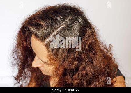 Nahaufnahme einer kaukasischen jungen Frau, die die Haarwurzeln auf weißem Hintergrund grau vergraut hat. Nachwachsende Wurzeln, die einer Wiederkölerung bedürfen. Anti-Aging-Pflege. Speicherplatz kopieren Stockfoto