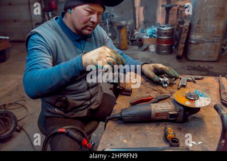 Porträt eines Schweißers in einem schwarzen Strickmütze auf dem Kopf am Arbeitsplatz mit einem Mikrofon im Ohr Stockfoto