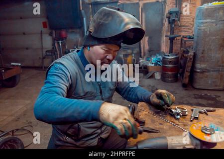 Porträt eines Schweißers in einem schwarzen Strickmütze auf dem Kopf am Arbeitsplatz mit einem Mikrofon im Ohr Stockfoto