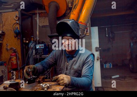 Porträt eines Schweißers in einem schwarzen Strickmütze auf dem Kopf am Arbeitsplatz mit einem Mikrofon im Ohr Stockfoto