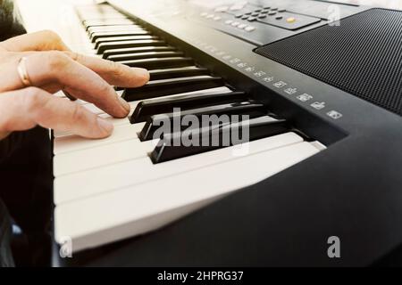 Männliche Hände spielen elektrische Synthesizer Digital Piano, Finger drücken Tasten. Musiker Mann Klavierspieler Begleiter auf schwarzen und weißen Keyboards bei a c Stockfoto