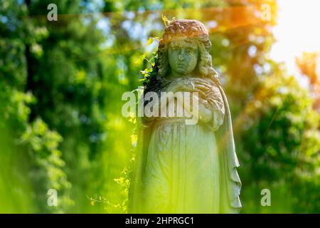 Der betende Engel faltete seine Arme über seine Brust. Fragment einer sehr alten Steinstatue. Horizontales Bild. Stockfoto