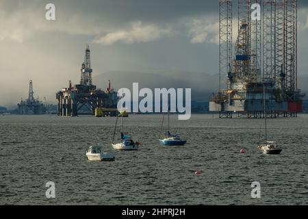 Ein Farbfoto von Ölbohrinseln im Cromarty Firth. Segelboote sind im Vordergrund zu sehen. Aus Cromarty. Stockfoto