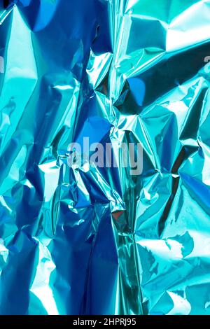 Abstrakt Silber Aluminium zerknittert Folie mehrfarbigen Hintergrund Textur reflektiert blaues Licht. Silber zerknittert Folie metallischen Glanz holographischen Effekt Stockfoto