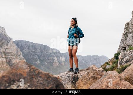 Lächelnde Frau Wanderer genießen die Aussicht. Junge, frauige Frau in Sportkleidung, die die Landschaft während einer Bergwanderung genießt. Stockfoto