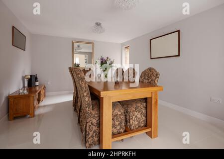 Swavesey, Cambridgeshire - August 22 2018: Esszimmer mit großem Holztisch, Stühlen mit Stoffbezug und glänzenden Porzellanfliesen in verschiedenen Farbtönen Stockfoto