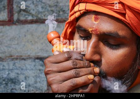 Kathmandu, Nepal. 23rd. Februar 2022. Ein Sadhu, ein Anhänger von Lord Shiva, raucht Marihuana aus einer Pfeife aus Lehm im Pashupatinath-Tempel, dem UNESCO-Weltkulturerbe, vor dem bevorstehenden Maha Shivaratri-Festival in Kathmandu, Nepal, am 23. Februar 2022. Maha shivaratri, ein Festival, das Lord Shiva gewidmet ist. Sadhus aus Nachbarländern sind vor dem bevorstehenden Maha Shivaratri Festival angekommen. (Foto: Abhishek Maharjan/Sipa USA) Quelle: SIPA USA/Alamy Live News Stockfoto