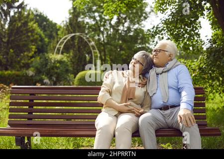 Ein romantisches, liebevolles Senioren-Paar, das auf der Bank sitzt und sich im Park umarmt Stockfoto