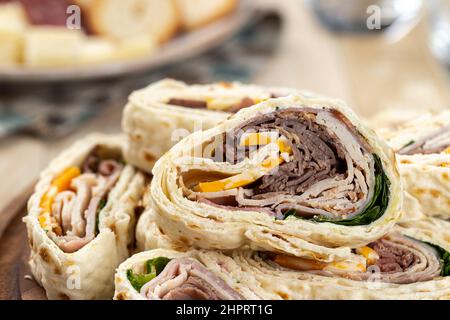 Nahaufnahme von Tortilla-Wraps, die mit Roastbeef, truthahn und Käse in einem Stapel auf einem Teller geschnitten wurden Stockfoto