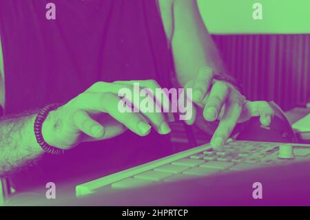 Seitenansicht eines jungen kaukasischen Mannes, der auf einem Midi-Controller Beat macht, elektronische Musik und kommerzielle urbane Musik produziert und komponiert. Stockfoto
