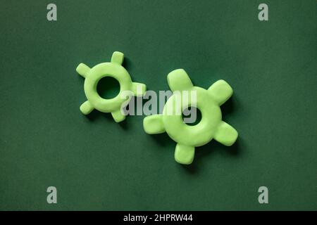 Zwei 3D-Gänge-Gänge-Getriebe in verschiedenen Größen auf grünem Hintergrund. Mechanismuselemente, Konzept des Fortschritts, Teamarbeit. Stockfoto