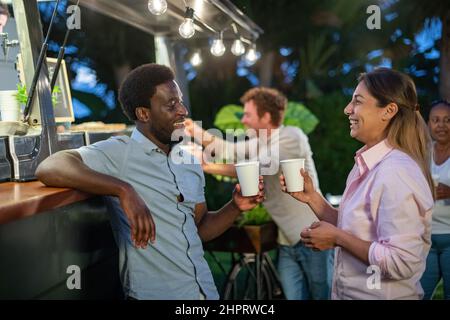 Fröhliches, multiethnisches Paar, das im Café heiße Getränke genießt Stockfoto