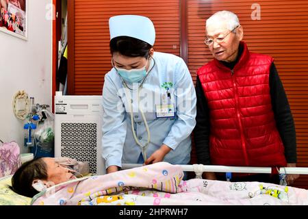 (220223) -- JINAN, 23. Februar 2022 (Xinhua) -- Krankenschwester Lian Ping (C) aus dem dritten Krankenhaus der Provinz Shandong versorgt einen Patienten in einem Wohngebiet des Bezirks Tianqiao, Stadt Jinan, ostchinesische Provinz Shandong, von Tür zu Tür., 23. Februar 2022. Die Provinz Shandong hat eine Online-Plattform eingerichtet, die Patienten eine Tür-zu-Tür-Pflege bietet. Patienten, die sich zu Hause erholen, können sich jetzt online für die Pflegedienste bewerben.Insgesamt haben sich 176 medizinische Einrichtungen und rund 15.000 qualifizierte und erfahrene Krankenschwestern auf der Plattform für die medizinische Versorgung registriert. Bis jetzt Stockfoto