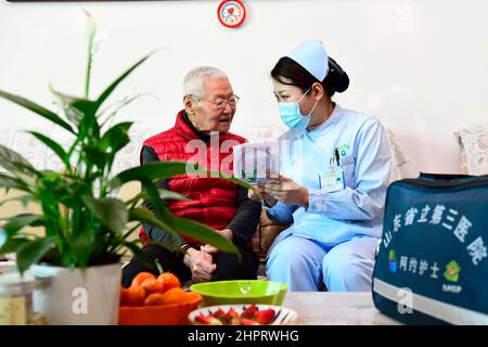 (220223) -- JINAN, 23. Februar 2022 (Xinhua) -- Krankenschwester Lian Ping(R) vom dritten Krankenhaus der Provinz Shandong erklärt den Pflegedienst, während ein Familienmitglied eines Patienten in einem Wohngebiet des Bezirks Tianqiao, Stadt Jinan, ostchinesische Provinz Shandong, zuhört, 23. Februar 2022. Die Provinz Shandong hat eine Online-Plattform eingerichtet, die Patienten eine Tür-zu-Tür-Pflege bietet. Patienten, die sich zu Hause erholen, können sich jetzt online für die Pflegedienste bewerben.Insgesamt haben sich 176 medizinische Einrichtungen und rund 15.000 qualifizierte und erfahrene Krankenschwestern auf der Plattform für die Medica-Versorgung angemeldet Stockfoto