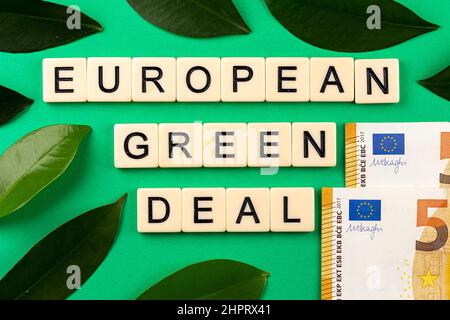 Satz „European Green Deal“, bestehend aus Buchstaben auf grünem Hintergrund mit grünen Laves und 50-Euro-Banknoten. Foto aufgenommen unter künstlichem, Stockfoto