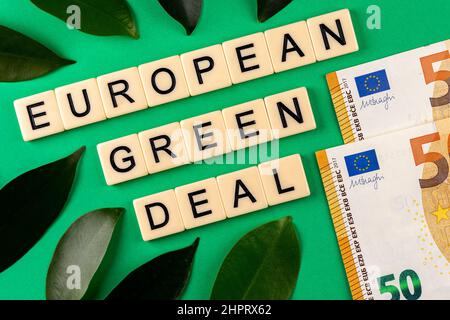 Satz „European Green Deal“, bestehend aus Buchstaben auf grünem Hintergrund mit grünen Laves und 50-Euro-Banknoten. Foto aufgenommen unter künstlichem, Stockfoto