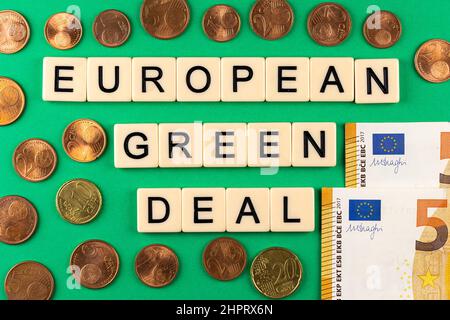 Satz „European Green Deal“, bestehend aus Buchstaben auf grünem Hintergrund mit Eurocent und 50-Euro-Banknoten. Foto unter künstlichem, s Stockfoto