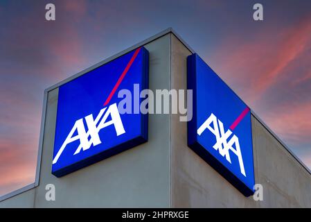 Fossano, Italien - 22. Februar 2022: AXA-Logo auf beleuchteten Schildern auf dem Gebäude auf dem farbenfrohen Himmel nach Sonnenuntergang, Axa ist französische Versicherung und Bankdienstleistungen Stockfoto