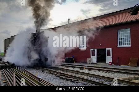 Eine restaurierte Dampfmaschine, die sich bereit für den Service macht, Rauch und Dampf an einem wolkigen Sommertag bläst Stockfoto