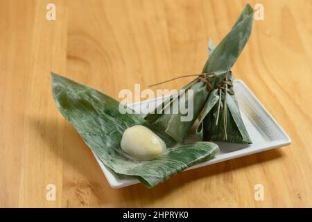 Japanisches Essen sasa Mochi Reiskuchen wickelt sich mit Bananenblatt in ein Gericht isoliert auf Holz Hintergrund Draufsicht Stockfoto