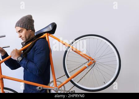 Mit dem Fahrrad zur Arbeit. Eine kurze Aufnahme eines trendigen jungen Mannes, der sein Fahrrad in der Halle trägt. Stockfoto