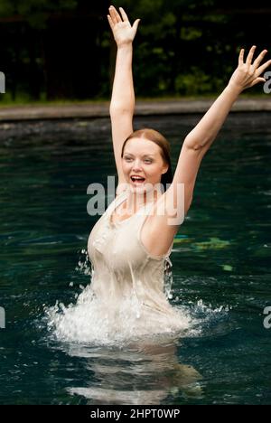 Frau im Bikini planschen und lächelnd im pool Stockfoto