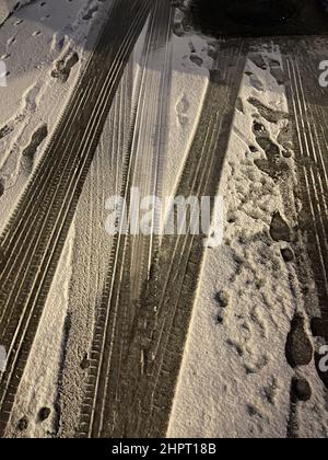 Nahaufnahme der verschneiten Landstraße, Reifenpiste, sonniger Wintertag Stockfoto