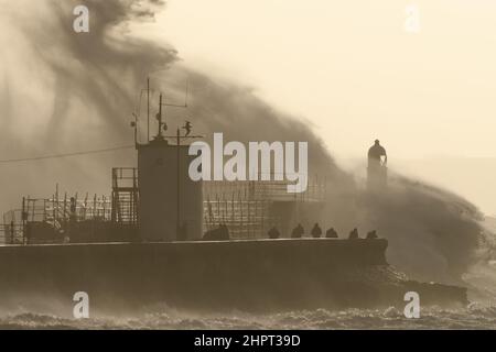 Porthcawl, South Wales, Großbritannien. 18. Februar 2022. Britisches Wetter: Große Wellen stürzen heute Morgen über die Verteidigung des Meeres, als der Sturm Eunice eintrifft. Stockfoto