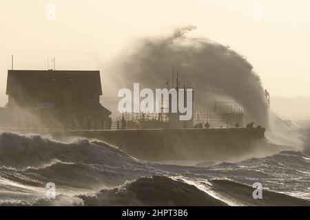 Porthcawl, South Wales, Großbritannien. 18. Februar 2022. Britisches Wetter: Große Wellen stürzen heute Morgen über die Verteidigung des Meeres, als der Sturm Eunice eintrifft. Stockfoto